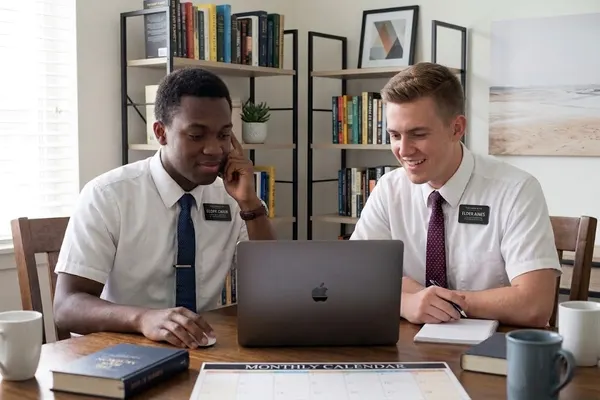Two missionaries reviewing workshop details on a laptop