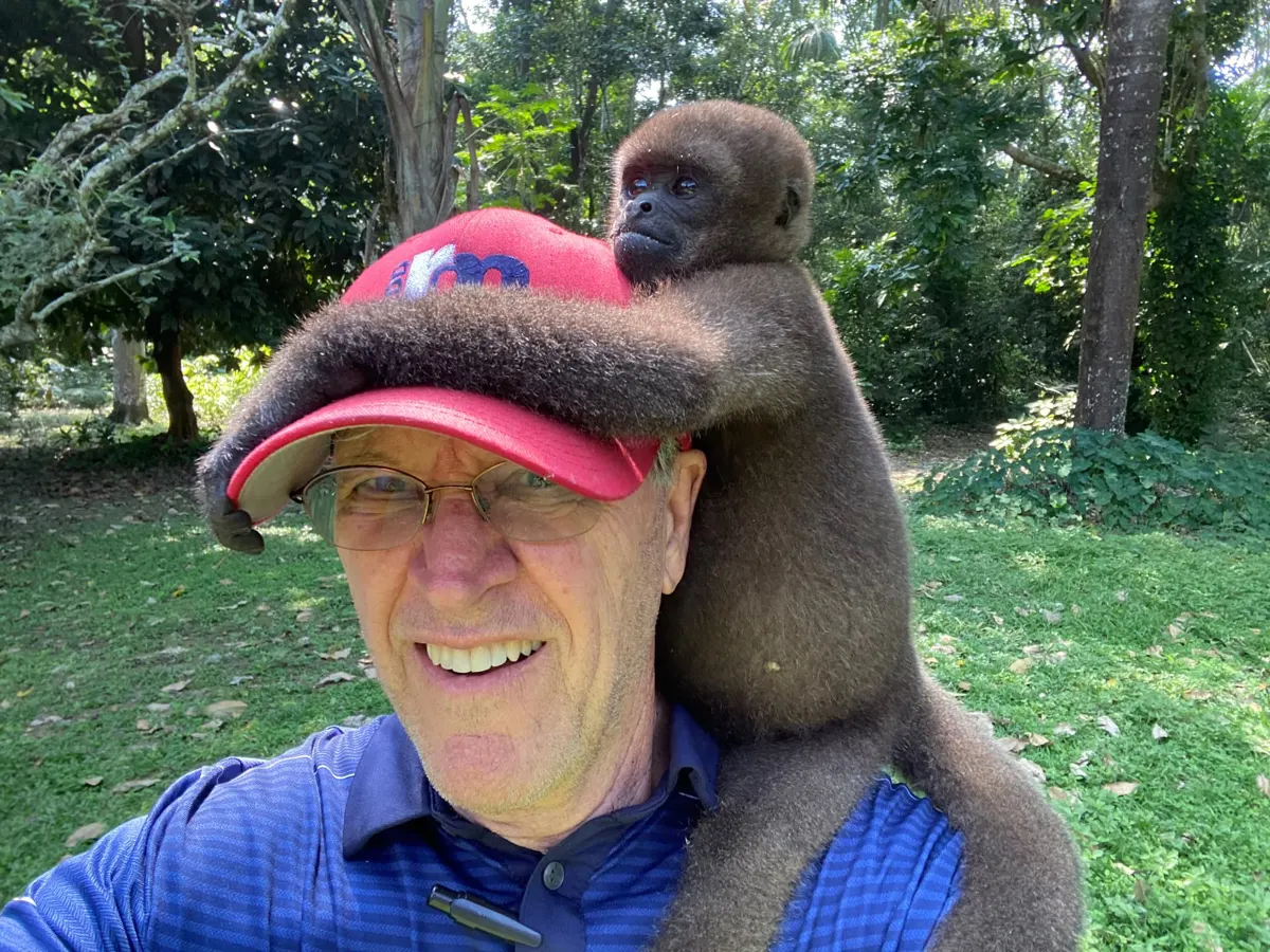 Dr. J.L. Redd outdoors in South America with a woolly monkey on his shoulder